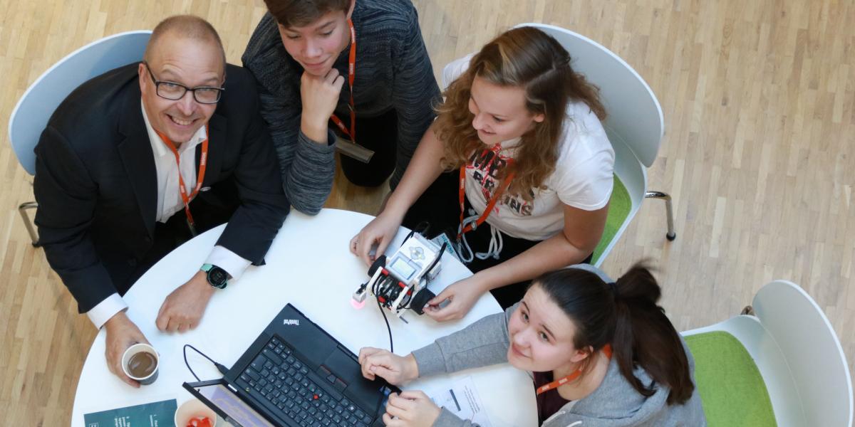 Direktør for Astra Mikkel Bohm sammen med en gruppe skoleelever, der programmerer robotter.