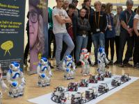En gruppe skoleelever ser på robotter, der står på række - klar til at blive programmeret.
